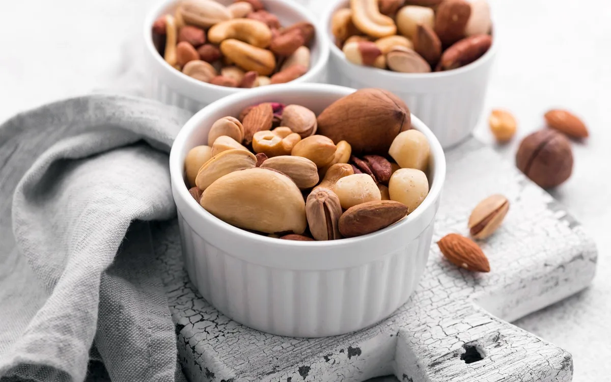 Various nuts arranged in white bowls on a white background, emphasizing their health benefits and natural goodness.