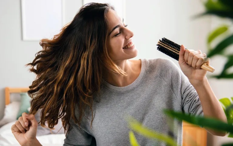 A woman using a hairbrush, representing the importance of hair care and the role of biotin in promoting hair growth.