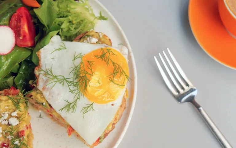 A plate of eggs with a fork beside it and a cup of coffee, emphasizing their role in a heart-healthy diet.