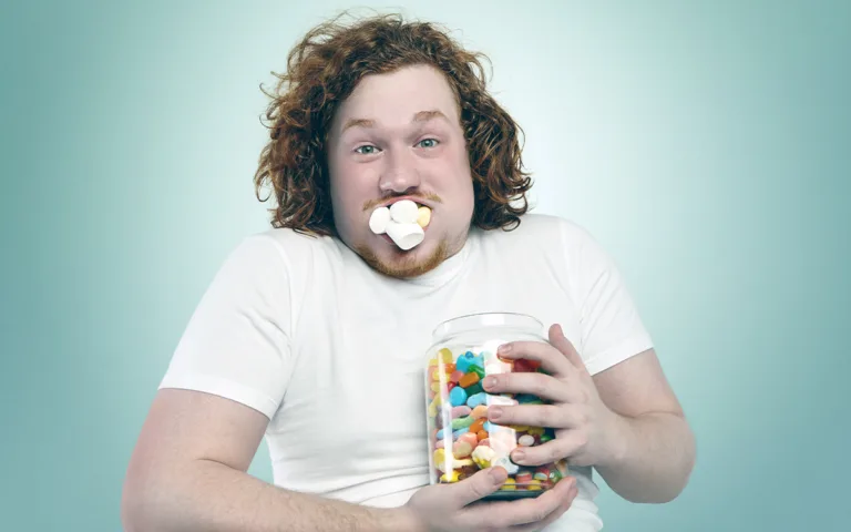 A man displays a jar of candy and a spoon, representing the journey to combat sugar cravings through nutritious alternatives.