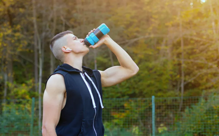 A man drinking from a bottle, highlighting the role of hydration and electrolytes in enhancing athletic performance during exercise.