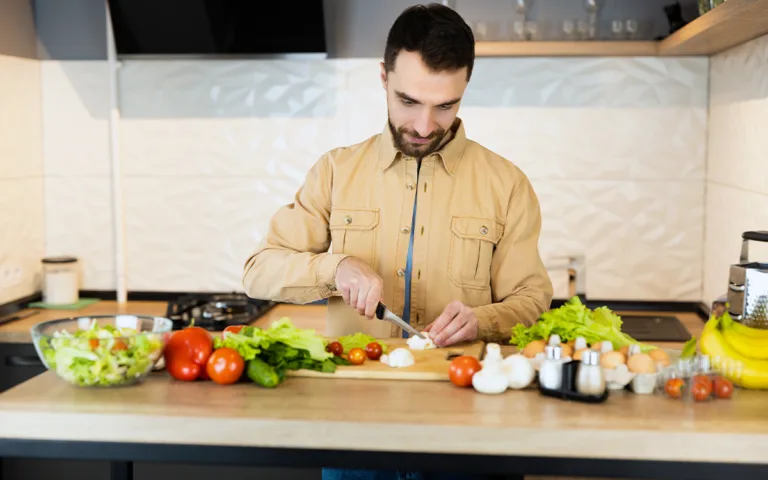 In a kitchen, a man prepares food, focusing on nutritious meals through smart cooking techniques and whole ingredients.