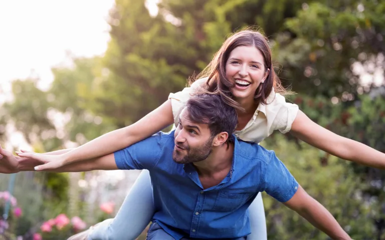 A couple laughing and having fun in a lush garden, representing the joy of shared moments and positive emotions.