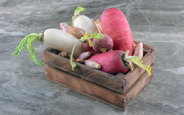 A wooden box containing assorted root vegetables like sweet potatoes, beets, and yams, rich in fiber and vitamins.