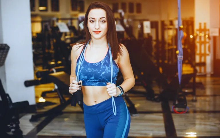 A woman in a blue sports bra and pants, showcasing a healthy glow from regular movement and exercise.