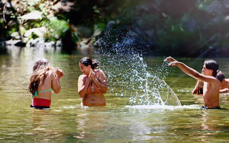 Friends playfully splashing water at each other, embracing the joy of nature and outdoor wellness.