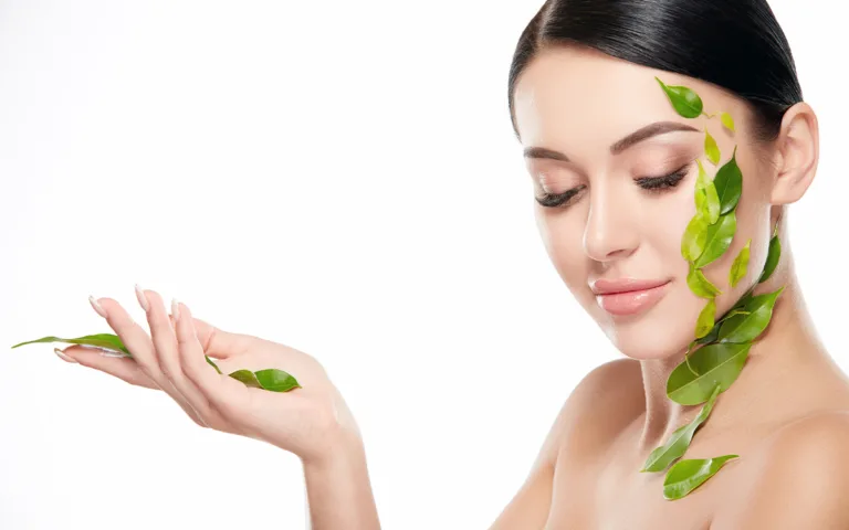 A stunning woman with green leaves on her face, representing the fusion of beauty and nature in vegan collagen skincare.