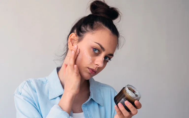 A woman holds a jar of face cream, showcasing the benefits of waterless skincare for enhanced beauty and eco-friendliness.