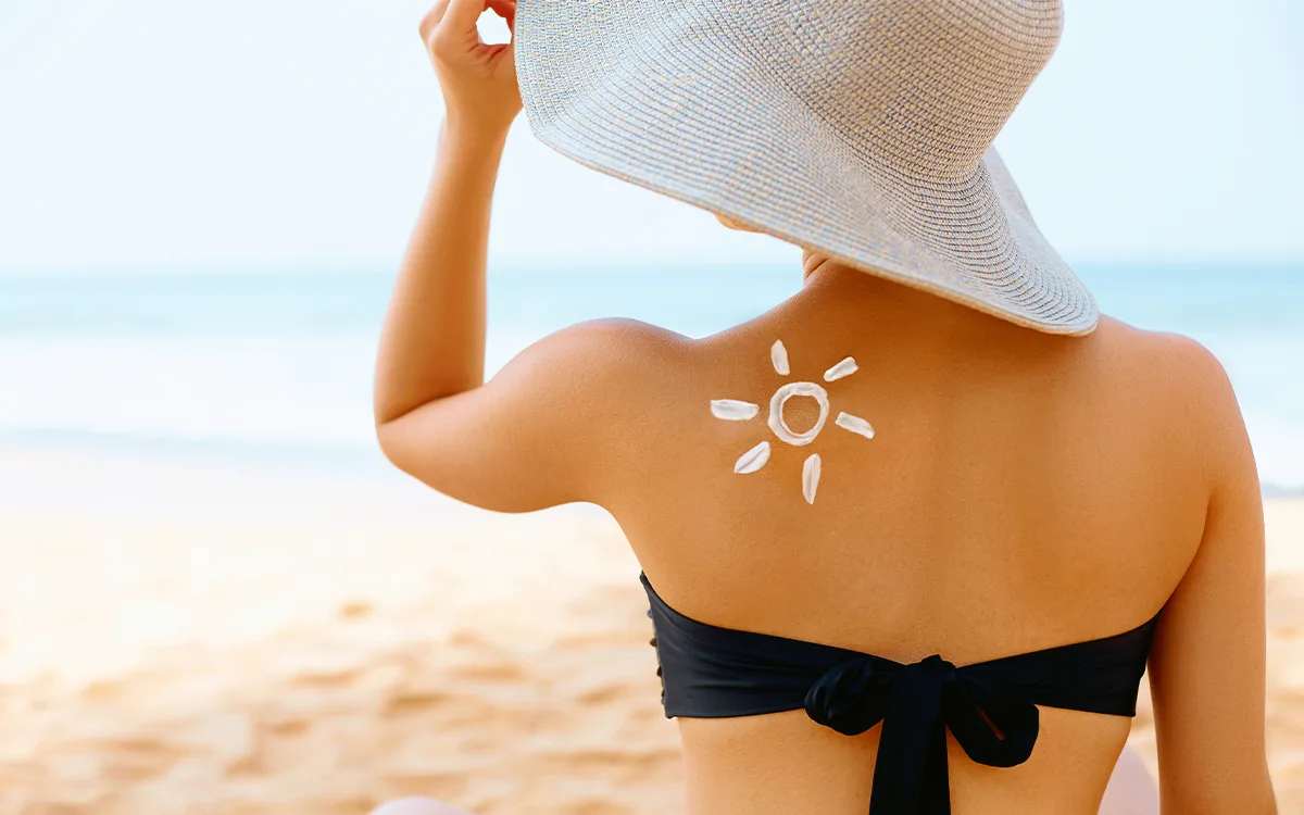 A woman in a bikini and hat relaxes on the beach, enjoying the sunny weather and the warmth of the sand.
