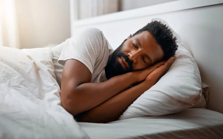 A man peacefully sleeping in bed, resting his head on a pillow, surrounded by a calm and serene atmosphere.