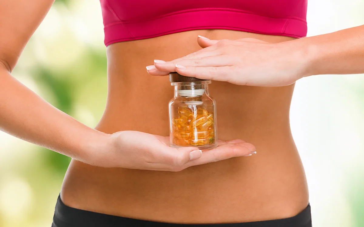 A woman holds a bottle of vitamin pills, suggesting the potential benefits of enzyme supplements for digestive health.