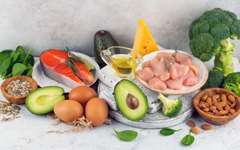 A variety of healthy foods including fish, eggs, broccoli, avocado, and nuts, representing balanced macronutrients for health.