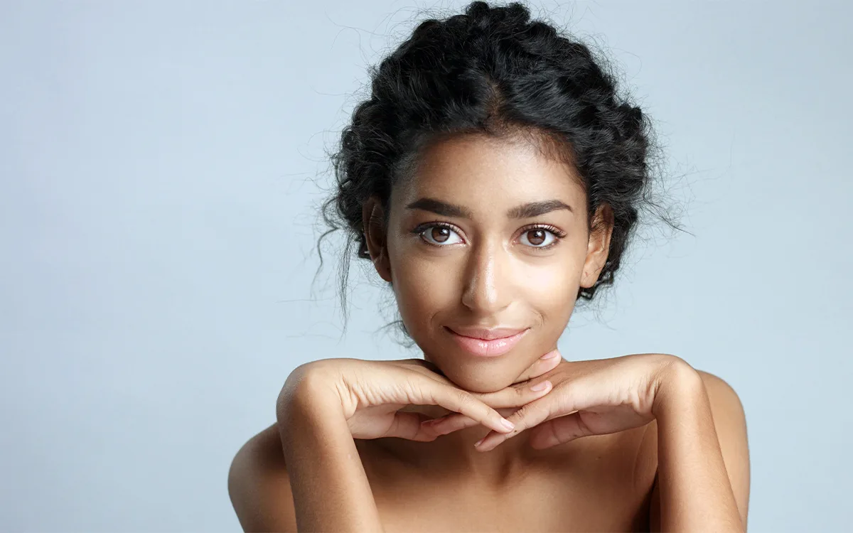 A woman with clear skin and a radiant smile, embodying the principles of skin minimalism and healthy skincare.
