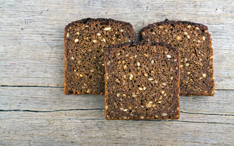 Slices of sprouted grain bread are arranged on a wooden table, highlighting the appeal of sprouted grain options.