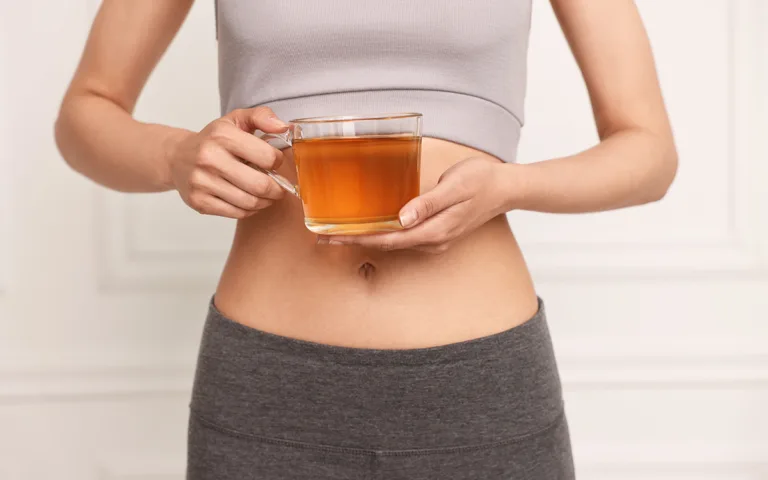 A woman holding a cup of tea, symbolizing natural remedies for digestive health and colon cleansing at home.