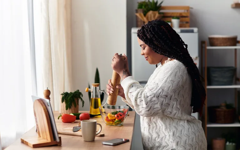 A woman prepares healthy food in a kitchen, focusing on nutritious ingredients for balanced meals and wellness.