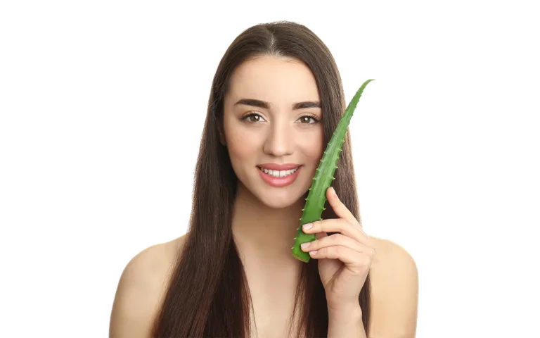 A woman holds a fresh aloe vera leaf, highlighting its benefits for dry hair and scalp health in natural hair care routines.