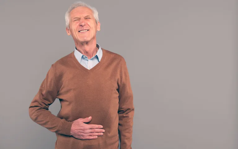 Older man with hands on his stomach, symbolizing the importance of gut health in aging and overall well-being.