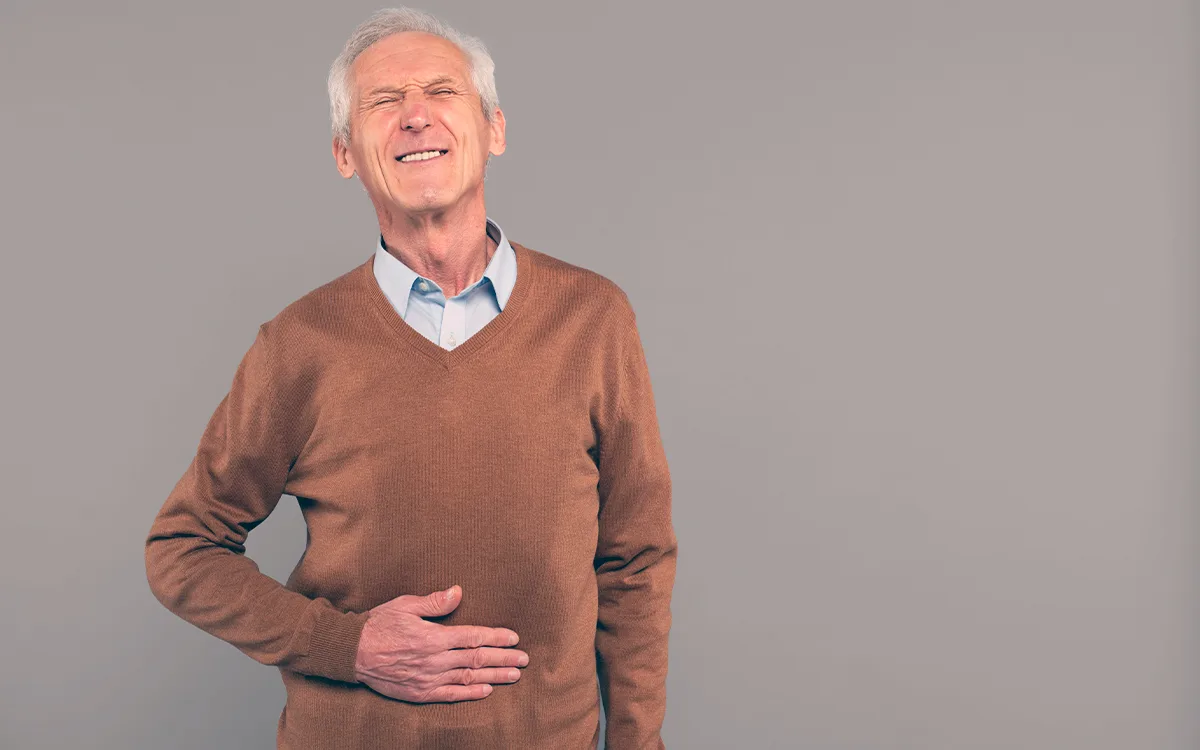 Older man with hands on his stomach, symbolizing the importance of gut health in aging and overall well-being.