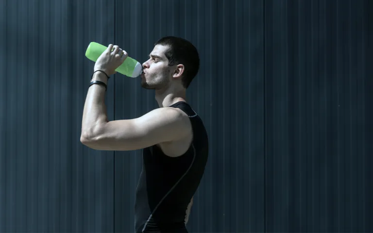 A man drinking from a bottle, illustrating the significance of hydration for exercise performance and general well-being.