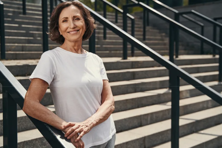 Active woman over 50 standing on outdoor steps, representing strength, mobility, and daily wellness supported by essential vitamins.