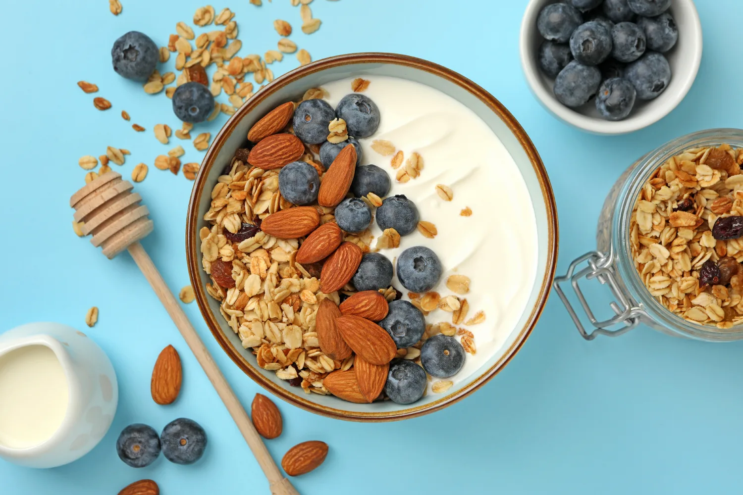 Bowl of yogurt topped with almonds, blueberries, and granola, highlighting a balanced snack option that supports steady glucose levels