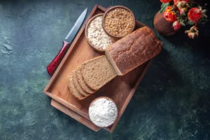 Whole grain bread with oats, wheat, and flour on a wooden tray, illustrating a natural swap from refined grains to whole grains for glucose support
