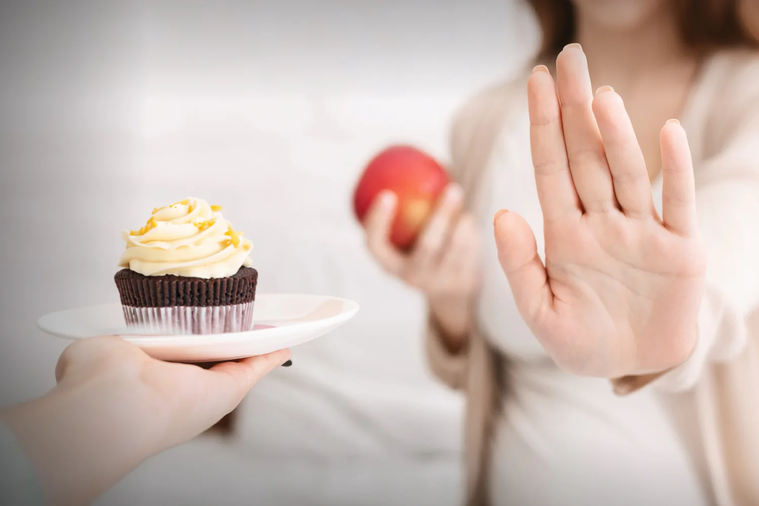 Person choosing an apple over a cupcake, representing a natural food swap to support balanced glucose levels and healthier daily choices