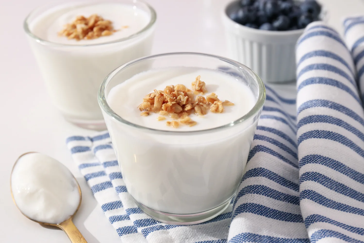 Glass bowls of yogurt topped with nuts and berries on a table, showing a light nighttime snack that may support better sleep during menopause.