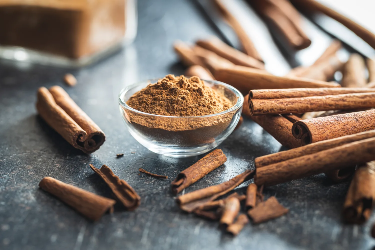 Ground cinnamon in a glass bowl with cinnamon sticks, a spice commonly associated with supporting healthy blood sugar balance.