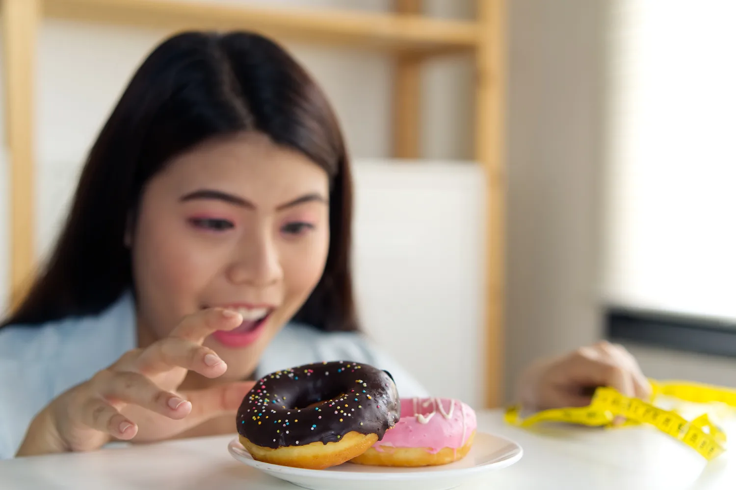 Woman reaching for sugary donuts, illustrating strong sugar cravings and the challenges of managing blood sugar balance naturally.