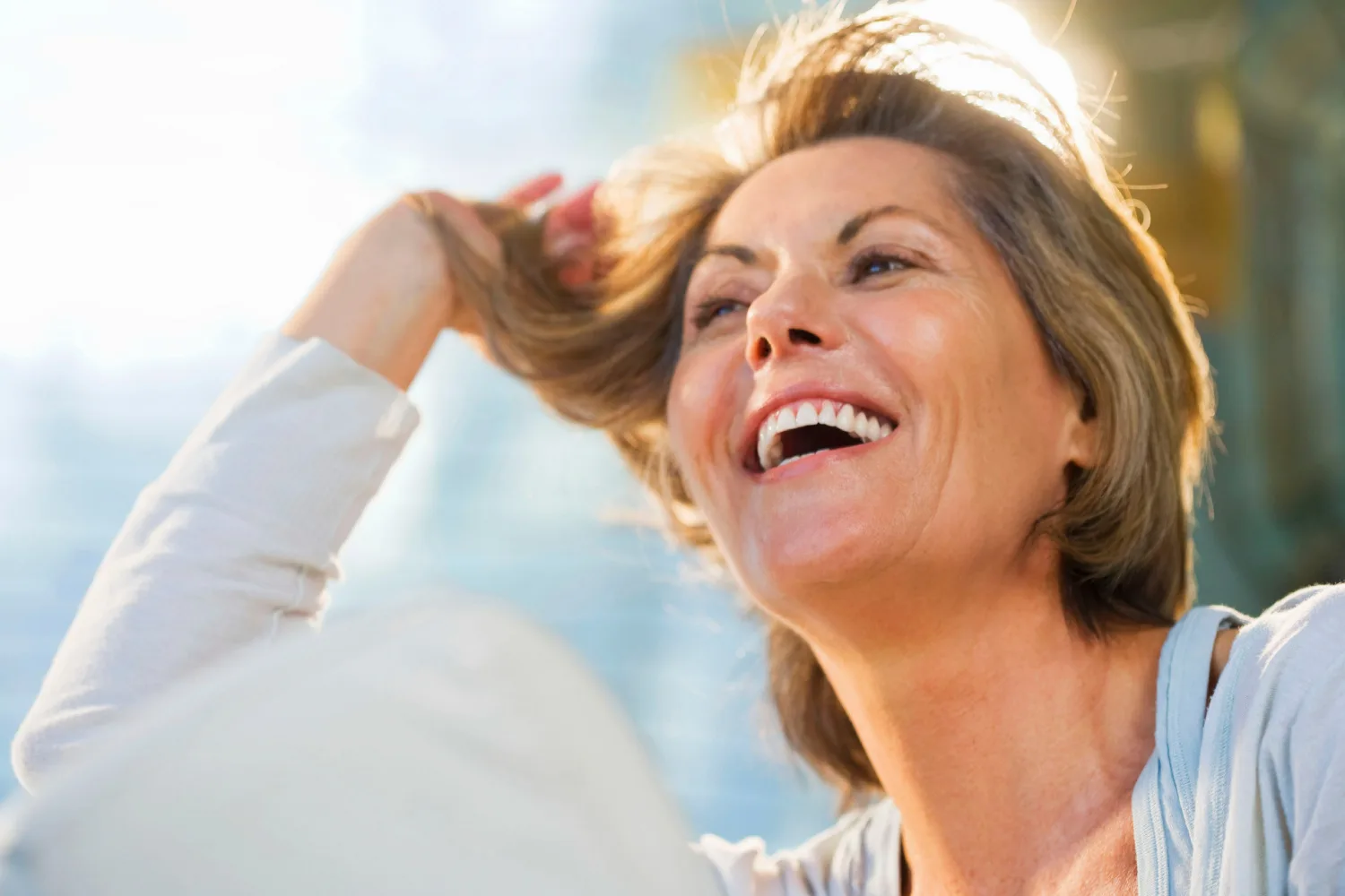 Happy menopausal woman enjoying healthy hair and improved volume outdoors, representing natural hair recovery after menopause