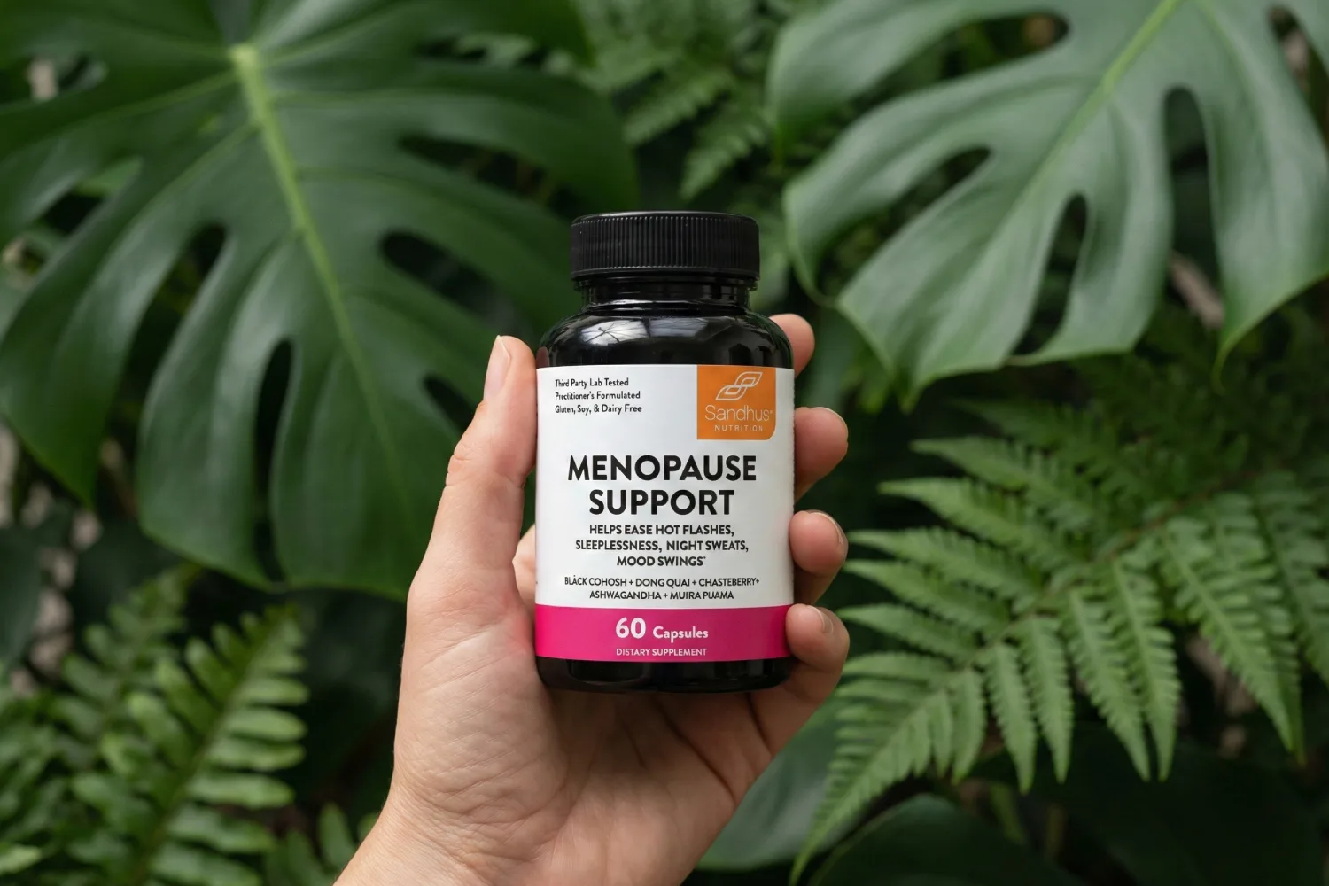 Hand holding a menopause support supplement bottle surrounded by green leaves, symbolizing natural solutions for thinning hair during menopause
