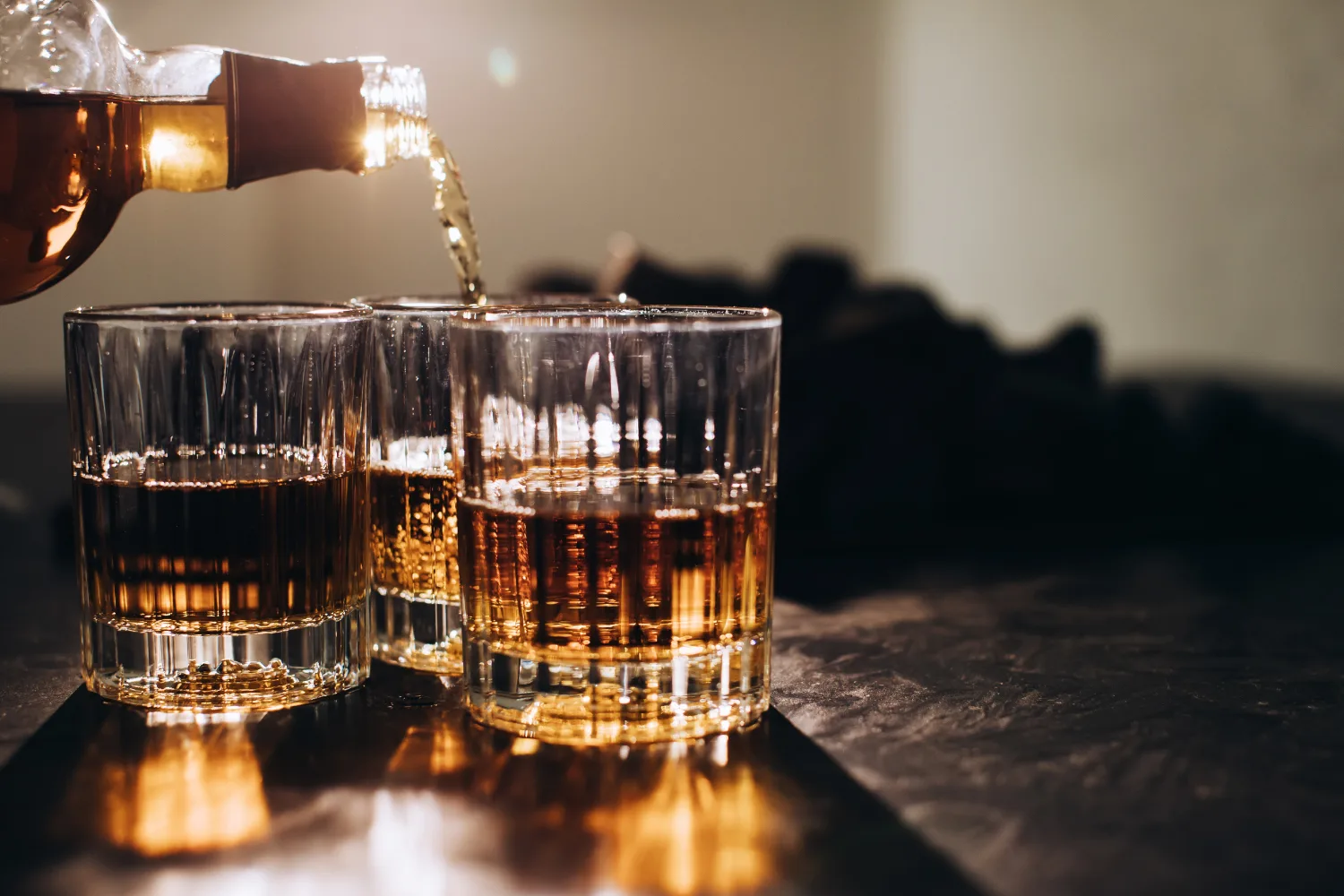 Glasses of alcoholic drink being poured, representing alcohol consumption that can worsen menopause symptoms like hot flashes and sleep disturbances.