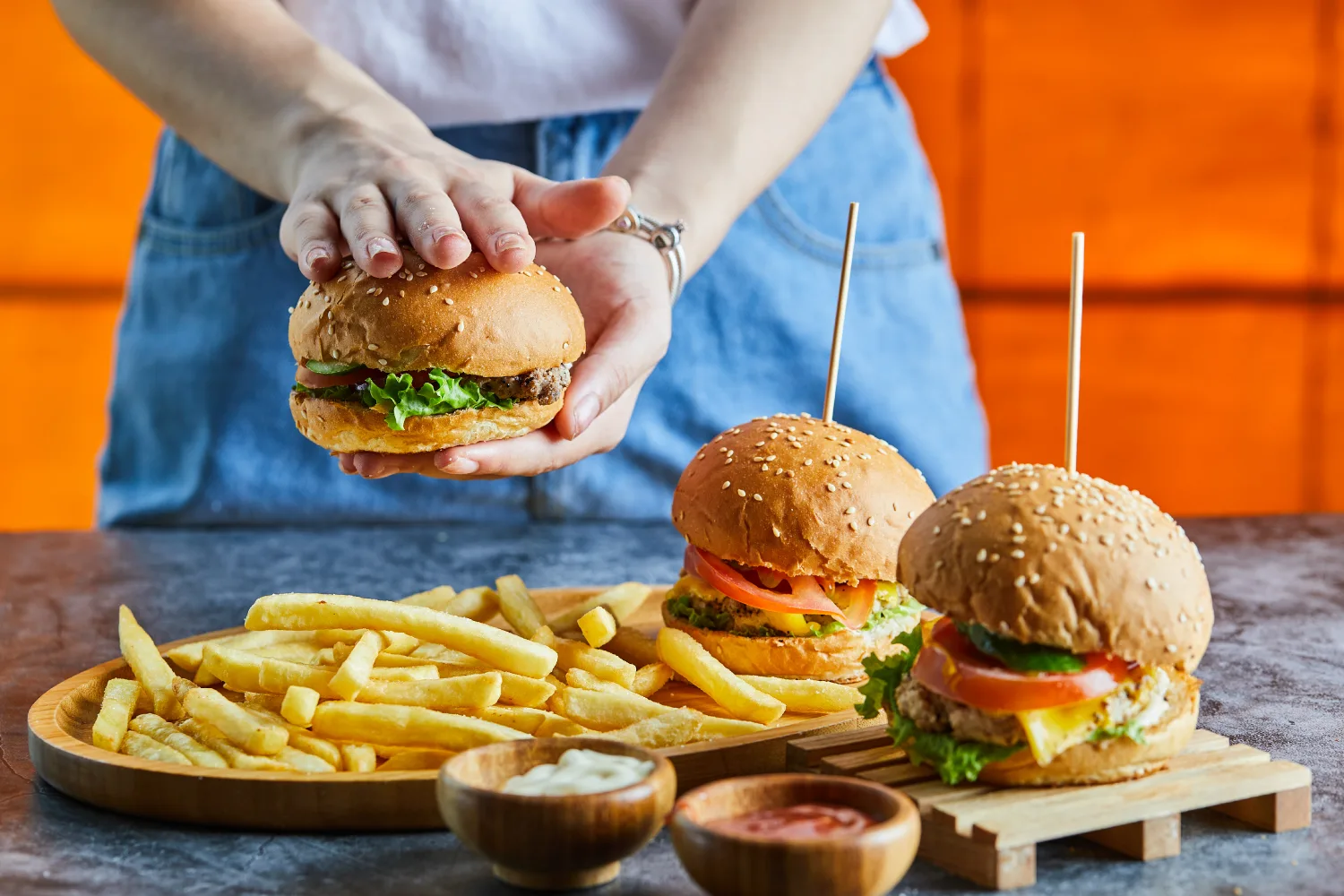 Hands holding burger and fries, representing processed and fast foods that may negatively affect hormones and increase inflammation during menopause.