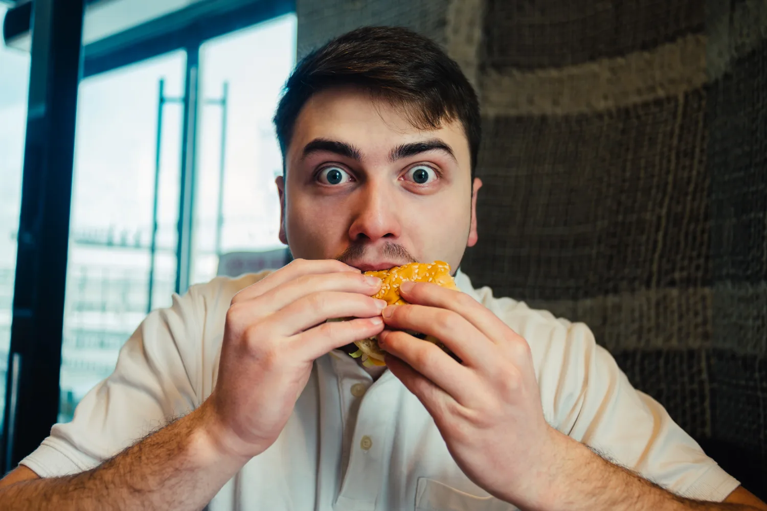 Man eating burger impulsively representing food noise driven by stress or habit and the impact of emotional eating on overall health