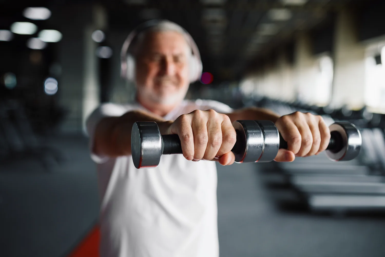 Senior man working out with dumbbells in a gym, symbolizing resistance training and creatine support for aging muscles