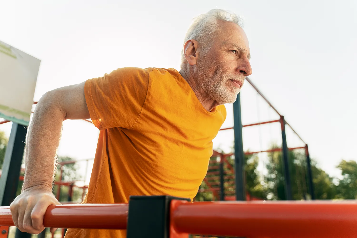 Older man performing bodyweight dips outdoors, highlighting fitness, muscle maintenance, and active aging after 60