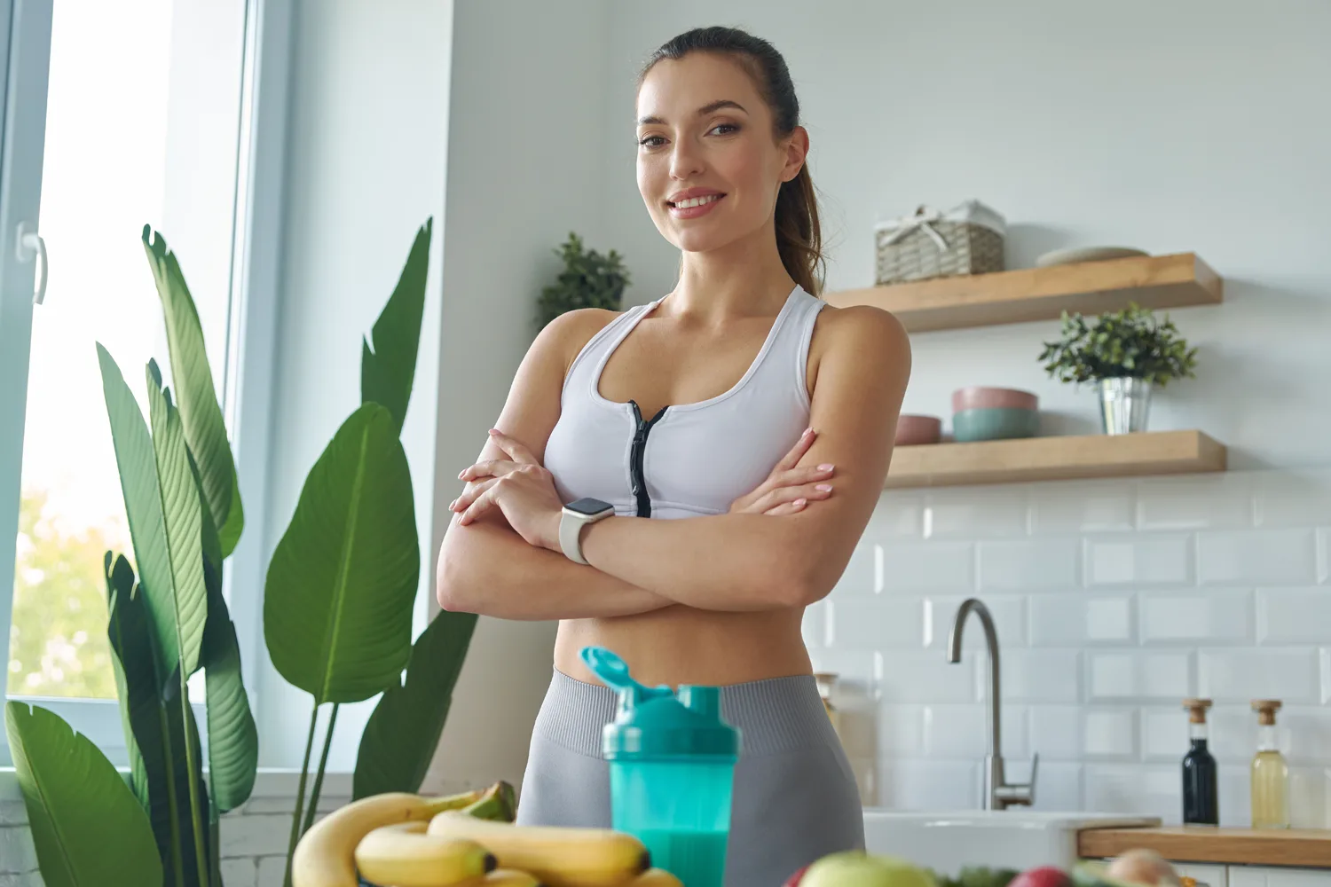 Fit woman in a kitchen with fruits and a shaker, symbolizing metabolism support and how timing berberine fits into daily routines