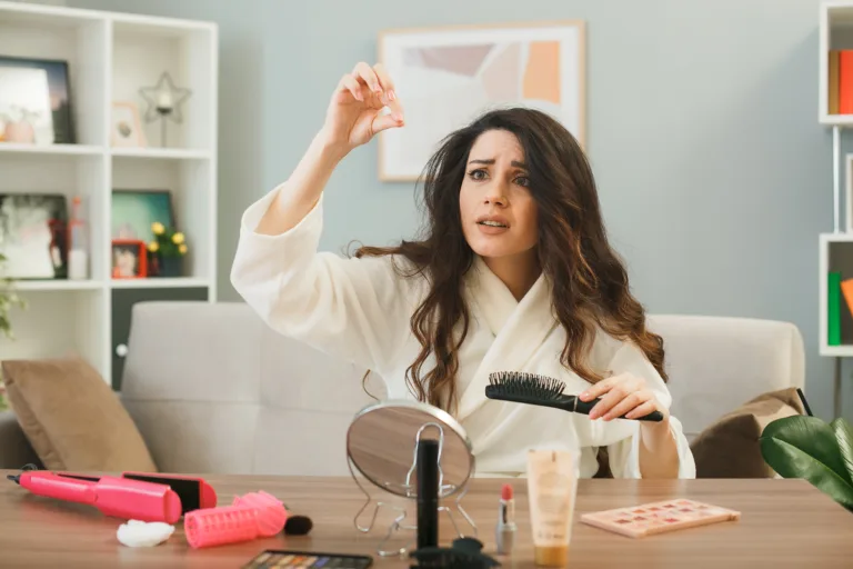 Woman concerned about hair fall holding hair strands with brush illustrating need for biotin and collagen supplementation.