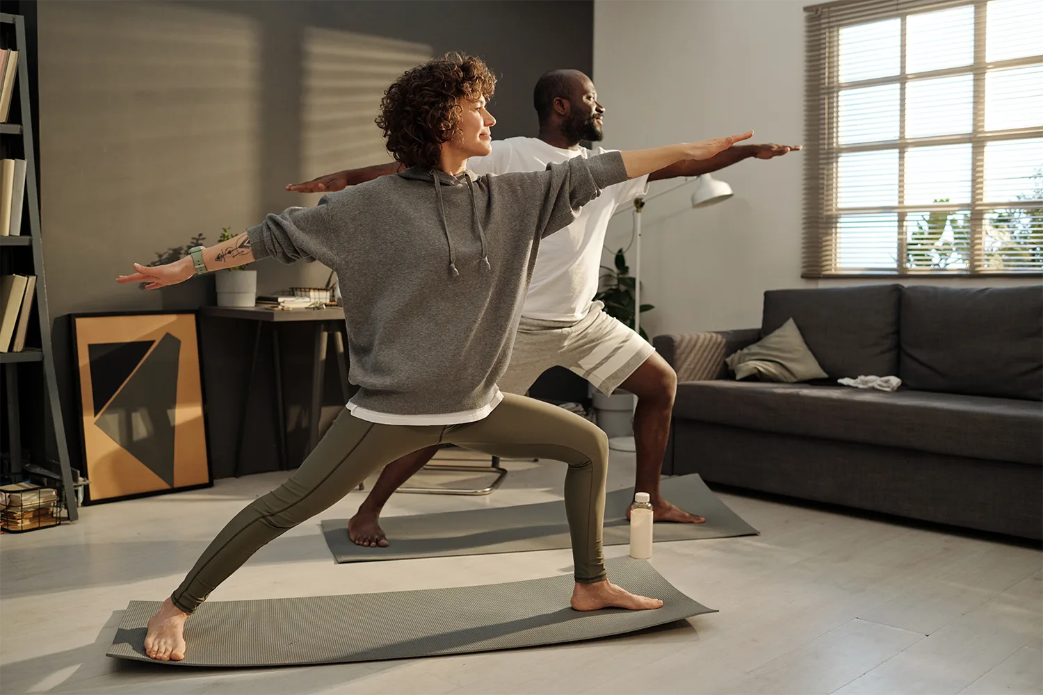 Two people practicing yoga at home representing movement, stress relief, and healthy recovery day wellness habits naturally