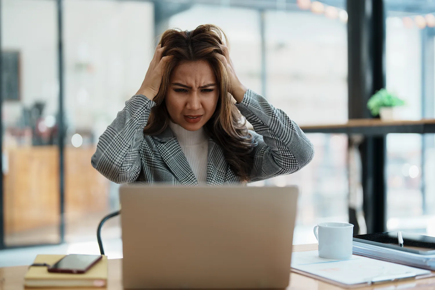 Stressed woman working on laptop showing how chronic stress and busy routines may affect overall liver wellness and energy